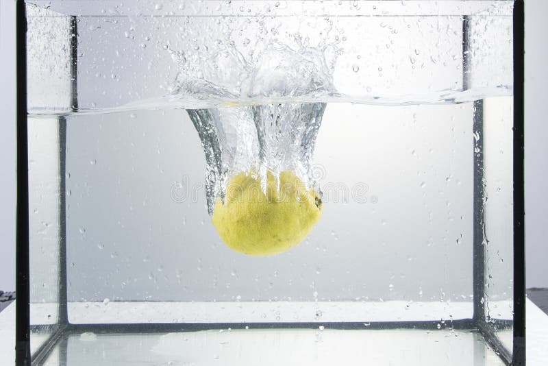 Eine Zitrone, fallend in das Wasser, mit dem Spritzen stockfoto