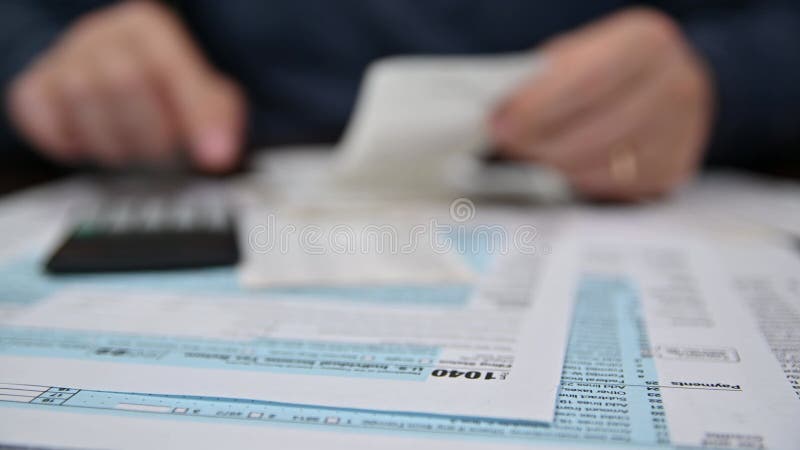 Einem Mann, der eine Einkommensteuererklärung nach Formblatt 1040 organisiert, und Einnahmen. verschwommener Hintergrund. Steuerze