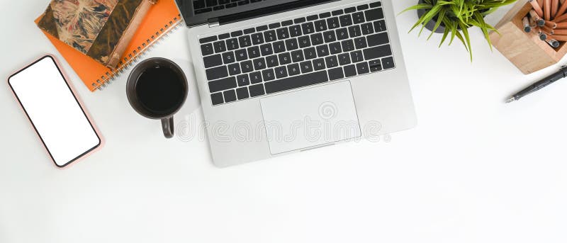 Einfacher Arbeitsplatz mit Laptop-Computer Smartphone-Kaffeetasse und Schreibwaren. stockfotografie