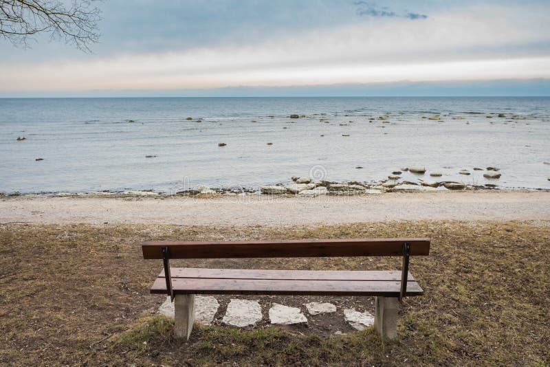 Einsame Holzbank auf dem Herbstmeer mit bewölktem Himmel lizenzfreies stockfoto Einsame Holzbank auf dem Herbstmeer mit bewölktem Himmel lizenzfreies stockfoto