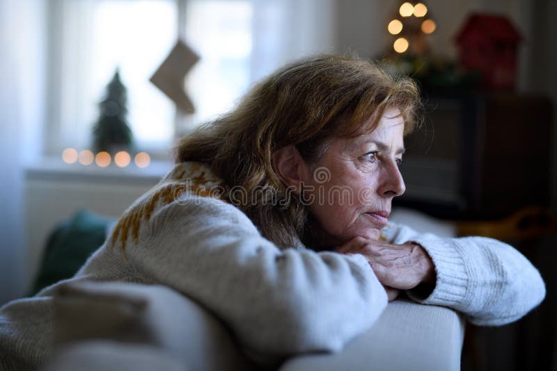 Einsame ältere Frau, die in Innenräumen auf Sofa Weihnachten Einsamkeitskonzept sitzt.