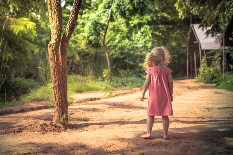 Einsames Kindermädchen, das barfuß allein auf ländlicher Landschaftsstraße unter Bäumen im Park steht und das Abstandskonzept chi lizenzfreies stockfoto Einsames Kindermädchen, das barfuß allein auf ländlicher Landschaftsstraße unter Bäumen im Park steht und das Abstandskonzept chi lizenzfreies stockfoto