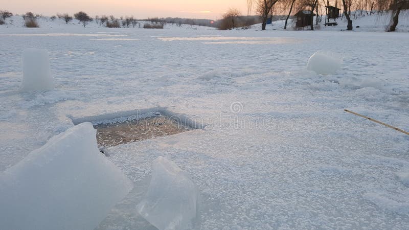 Ice fishing hole cut into frozen lake on sunny day. Ice fishing hole cut into frozen lake on sunny day.