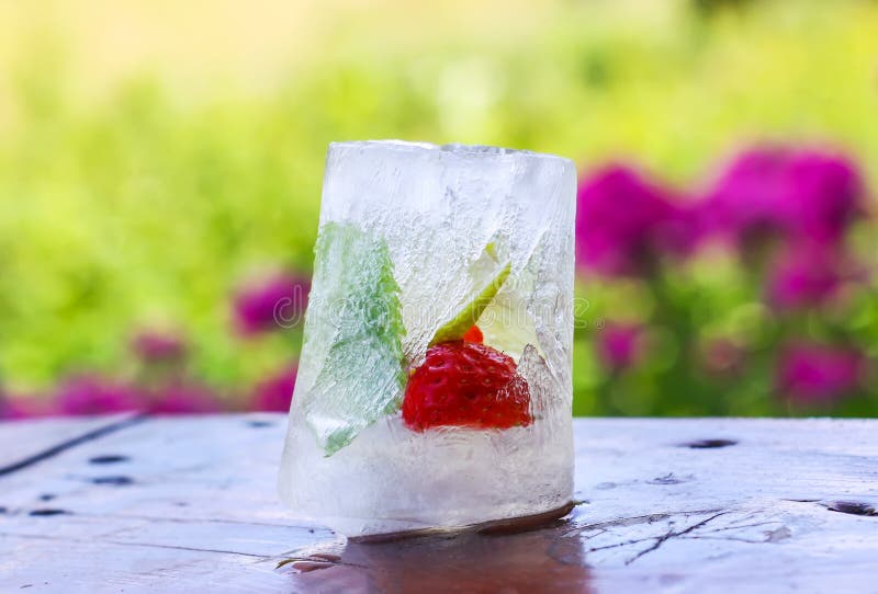 Eiswürfel mit Erdbeere, Zitrone und frischen grünen tadellosen Blättern auf Holzoberfläche draußen lizenzfreie stockfotografie Eiswürfel mit Erdbeere, Zitrone und frischen grünen tadellosen Blättern auf Holzoberfläche draußen lizenzfreie stockfotografie