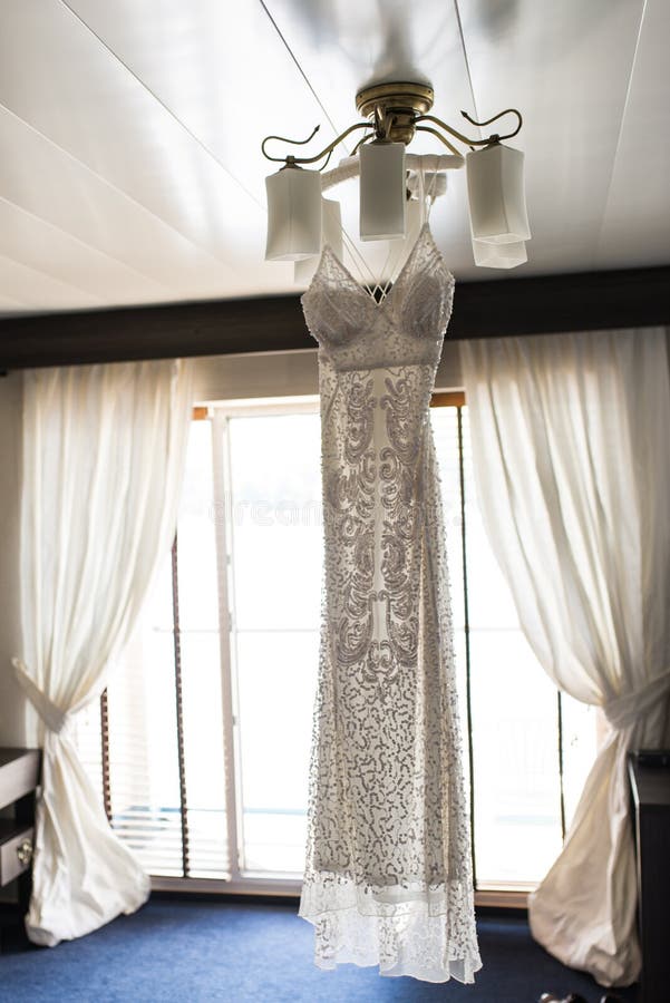 Ejecución de lujo del vestido de boda en la lámpara en una habitación Vestido nupcial bridesmaids fotografía de archivo libre de regalías Ejecución de lujo del vestido de boda en la lámpara en una habitación Vestido nupcial bridesmaids fotografía de archivo libre de regalías
