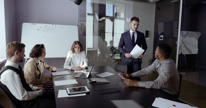 Ejecutivos de la empresa consultando al inversor de un cliente comercial masculino en una reunión multiétnica Equipo profesional almacen de video