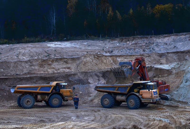 Excavator loading sand into dumper truck. Quarry for the extraction of minerals. Excavator loading sand into dumper truck. Quarry for the extraction of minerals