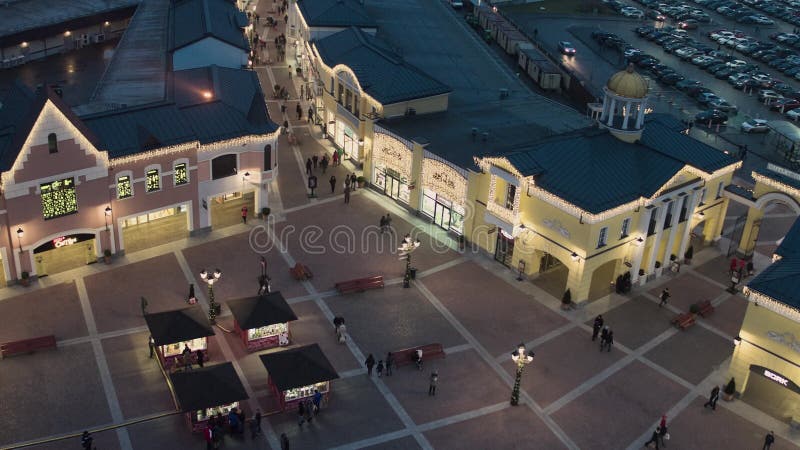 El abejón muestra edificios de tienda que hacen compras con la iluminación llena de gente que camina