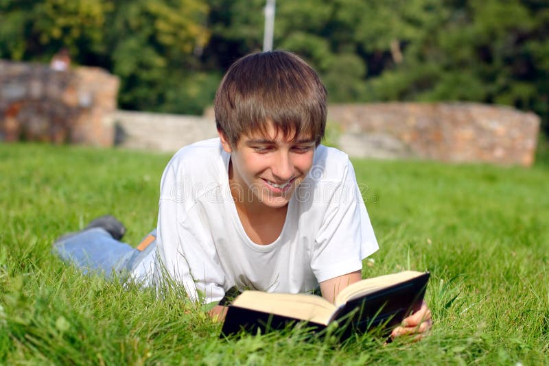 The teenager reads the book on a summer meadow. The teenager reads the book on a summer meadow