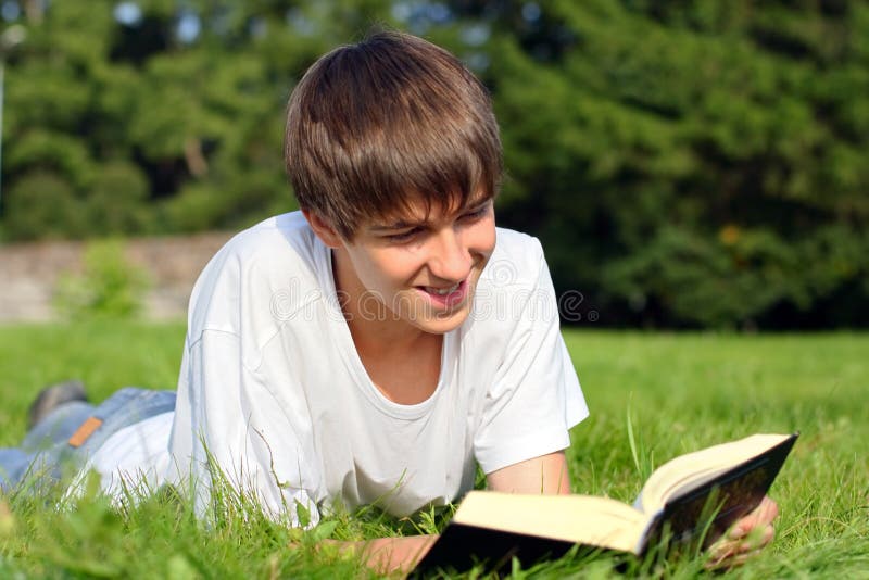 The teenager reads the book on a summer meadow. The teenager reads the book on a summer meadow