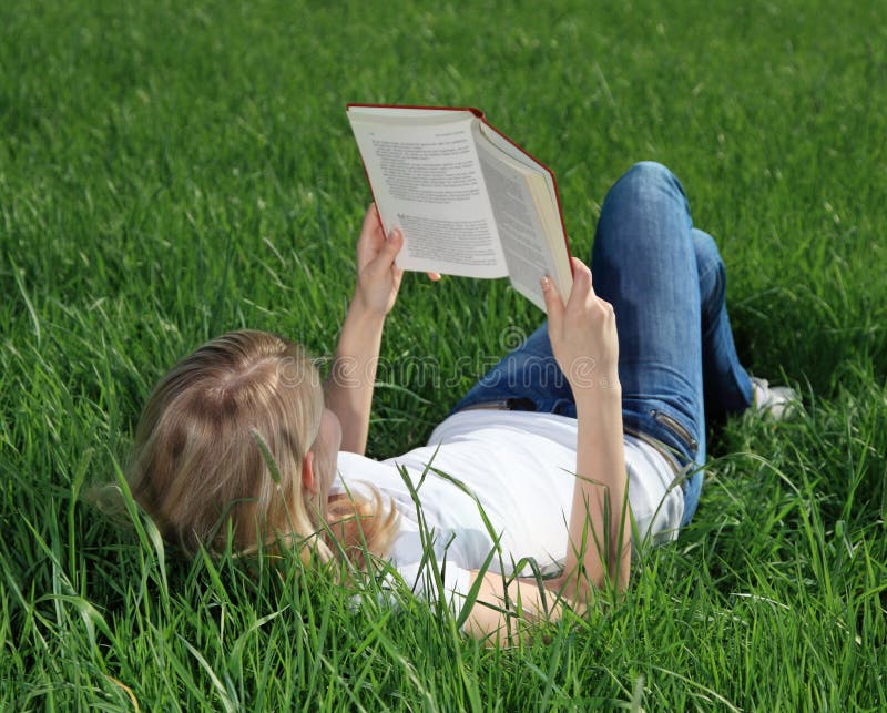 Attractive teenage girl reading a book on meadow. Attractive teenage girl reading a book on meadow.