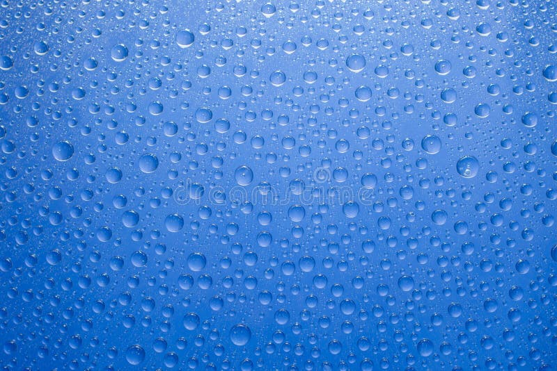 El agua cae el fondo azul Gotas del agua en el fondo de cristal