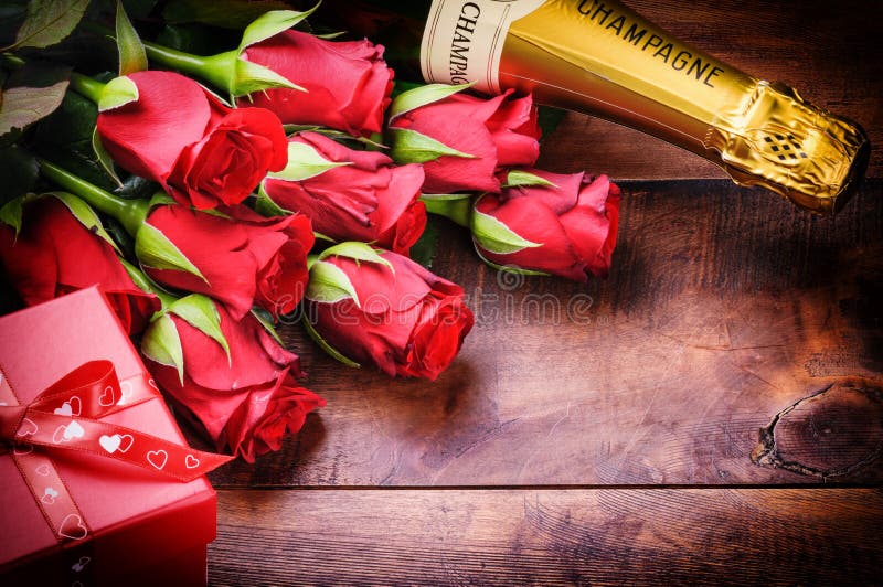 El ajuste de la tarjeta del día de San Valentín con las rosas rojas, el champán y el regalo