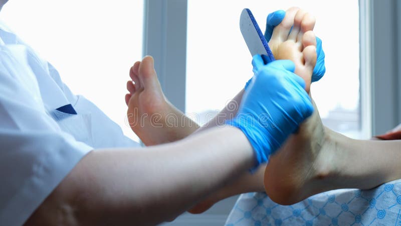 El amo de la pedicura limpia la vieja capa de piel de pies con una pisada del pie - pedicura en el cierre de la oficina para arri foto de archivo libre de regalías El amo de la pedicura limpia la vieja capa de piel de pies con una pisada del pie - pedicura en el cierre de la oficina para arri foto de archivo libre de regalías