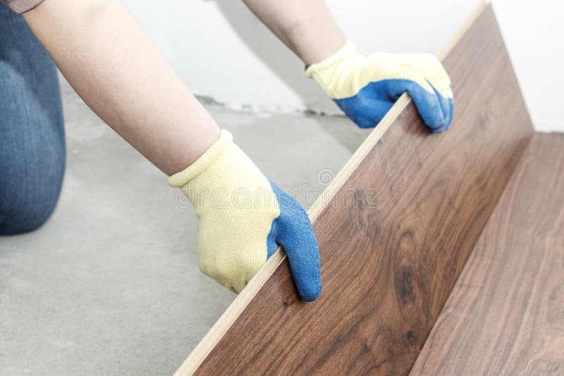 el amo en guantes azules hace la colocación entarimado hay un nivel y martillo de goma fotografía de archivo libre de regalías el amo en guantes azules hace la colocación entarimado hay un nivel y martillo de goma fotografía de archivo libre de regalías