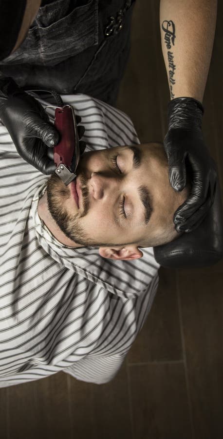 El amo hace la corrección de las barbas en salón de la barbería Ciérrese encima de la foto foto de archivo El amo hace la corrección de las barbas en salón de la barbería Ciérrese encima de la foto foto de archivo