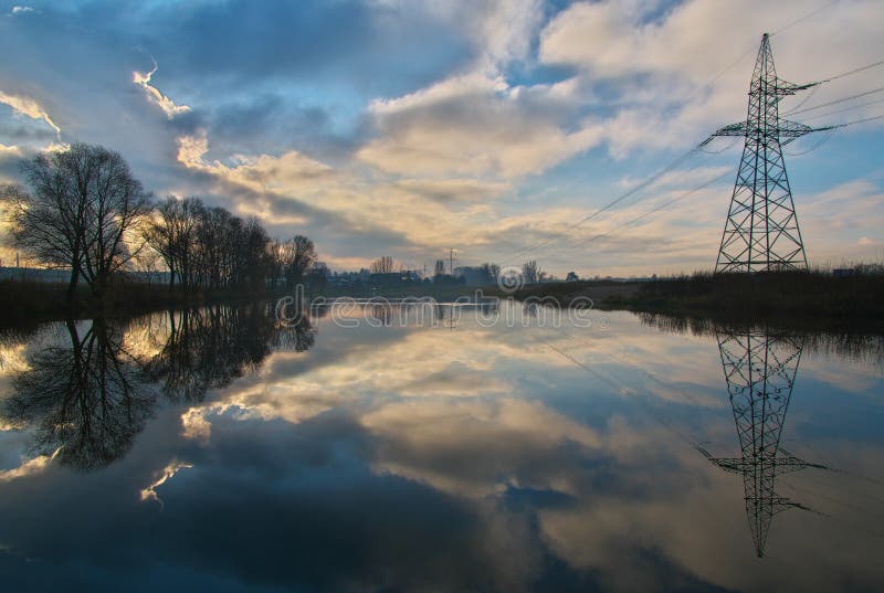 El apacible paisaje matutino con niebla y cielo sobre el estanque rodeado de árboles y torres eléctricas con el hermoso reflejo imagenes de archivo El apacible paisaje matutino con niebla y cielo sobre el estanque rodeado de árboles y torres eléctricas con el hermoso reflejo imagenes de archivo