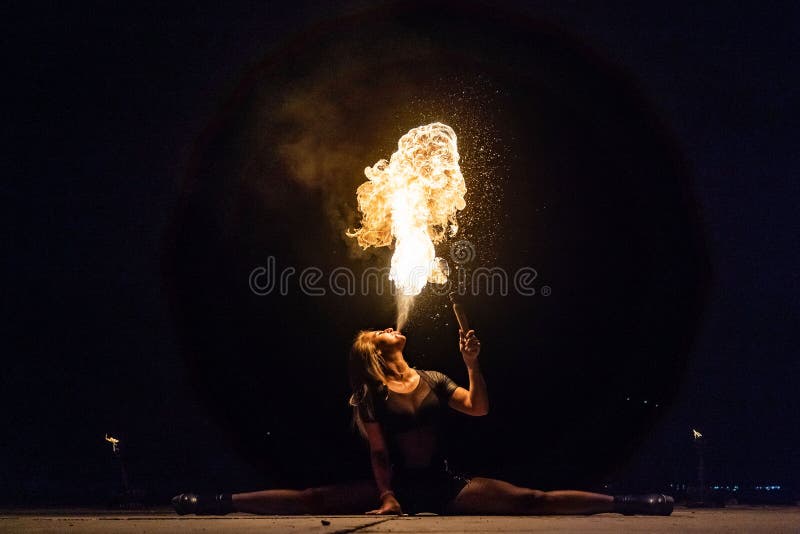 El artista de la demostración del fuego respira el fuego en la oscuridad imagen de archivo El artista de la demostración del fuego respira el fuego en la oscuridad imagen de archivo