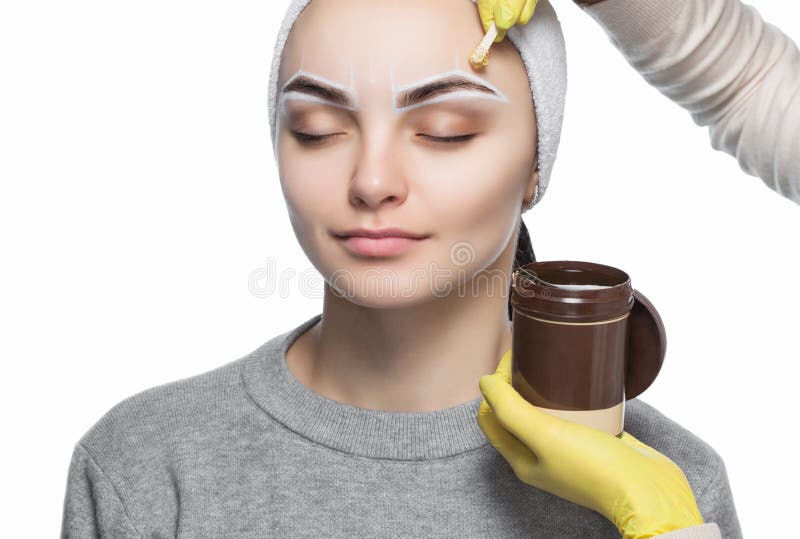 El artista de maquillaje despluma sus cejas, antes del procedimiento del maquillaje permanente imagen de archivo El artista de maquillaje despluma sus cejas, antes del procedimiento del maquillaje permanente imagen de archivo