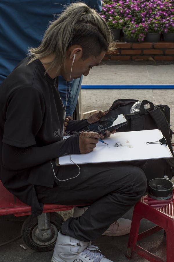 El artista vietnamita extrae un retrato de una imagen en su foto móvil, en una calle de Ho Chi Minh City, Vietnam fotos de archivo libres de regalías El artista vietnamita extrae un retrato de una imagen en su foto móvil, en una calle de Ho Chi Minh City, Vietnam fotos de archivo libres de regalías