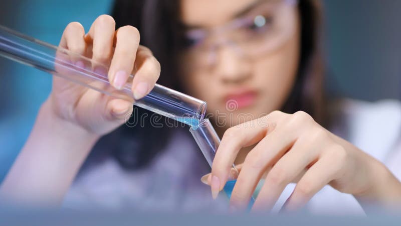 El ayudante femenino asiático del biólogo conduce el experimento científico que estudia la reacción química