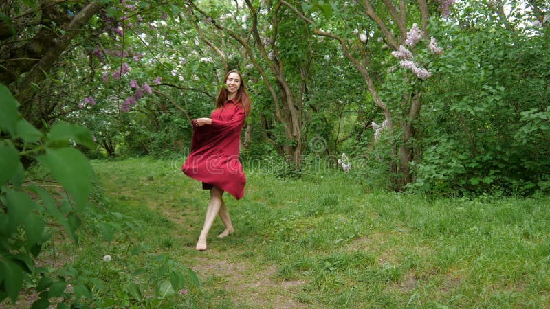 El bailarín de la chica joven en vestido del marsala está viniendo al aire libre