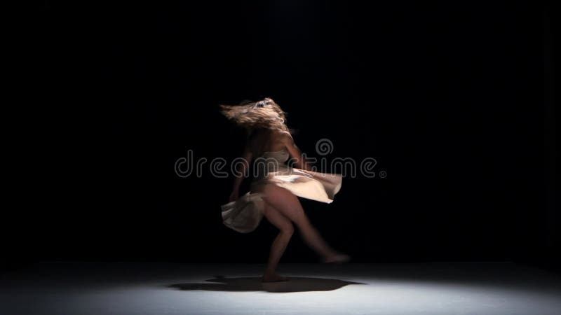 El bailarín de la mujer joven que baila danza contemporánea se mueve, salta y hace una fractura, en negro, sombra almacen de metraje de vídeo