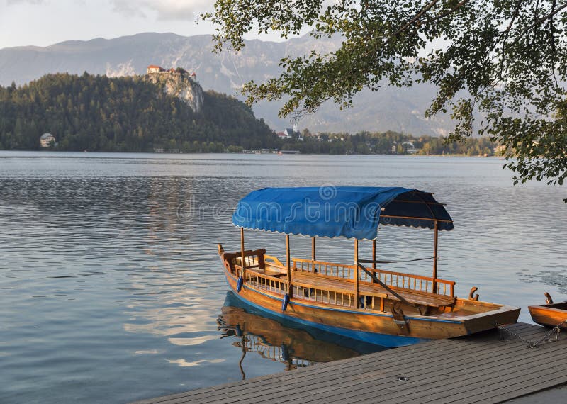 El barco en el lago Bled pasó por alto por el castillo en la puesta del sol imagen de archivo El barco en el lago Bled pasó por alto por el castillo en la puesta del sol imagen de archivo