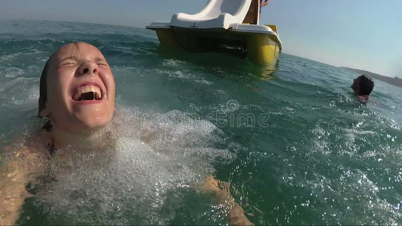 El barco feliz de la muchacha arranca la colina en el mar, visión desde el agua