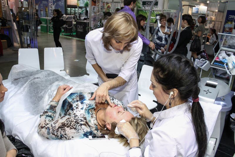 MOSCOW - OCTOBER 26: Beautician performs a laser procedure at the international exhibition of professional cosmetics and beauty salon equipment INTERCHARM on October 26, 2011 in Moscow. MOSCOW - OCTOBER 26: Beautician performs a laser procedure at the international exhibition of professional cosmetics and beauty salon equipment INTERCHARM on October 26, 2011 in Moscow