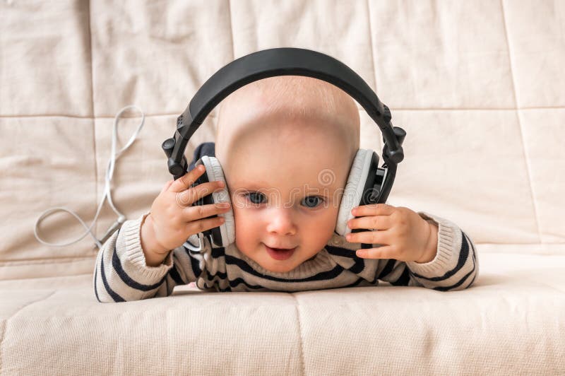 El Bebé Lindo Con Los Auriculares Escucha La Música En Casa Imagen
