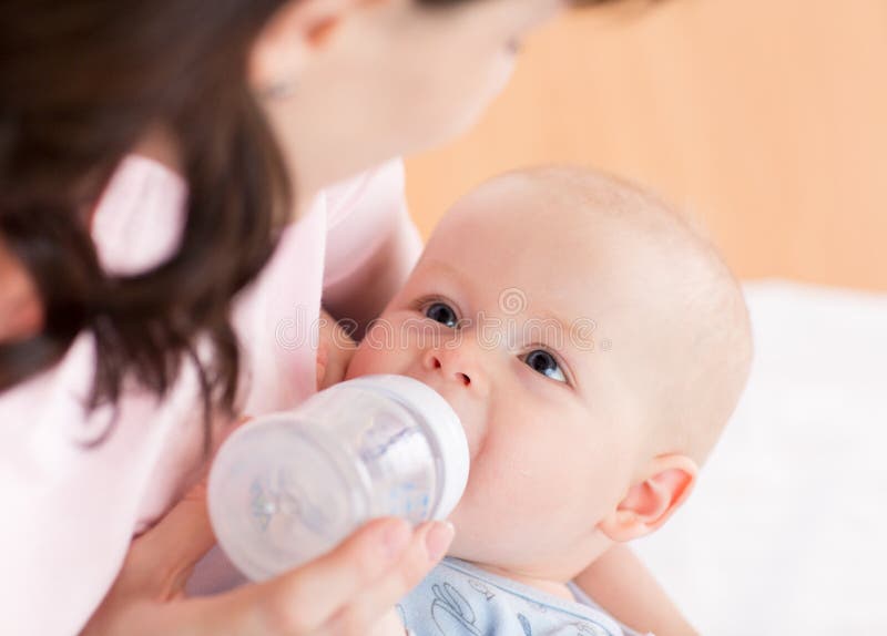 Pequeño bebé bebiendo de un biberón imagen de archivo