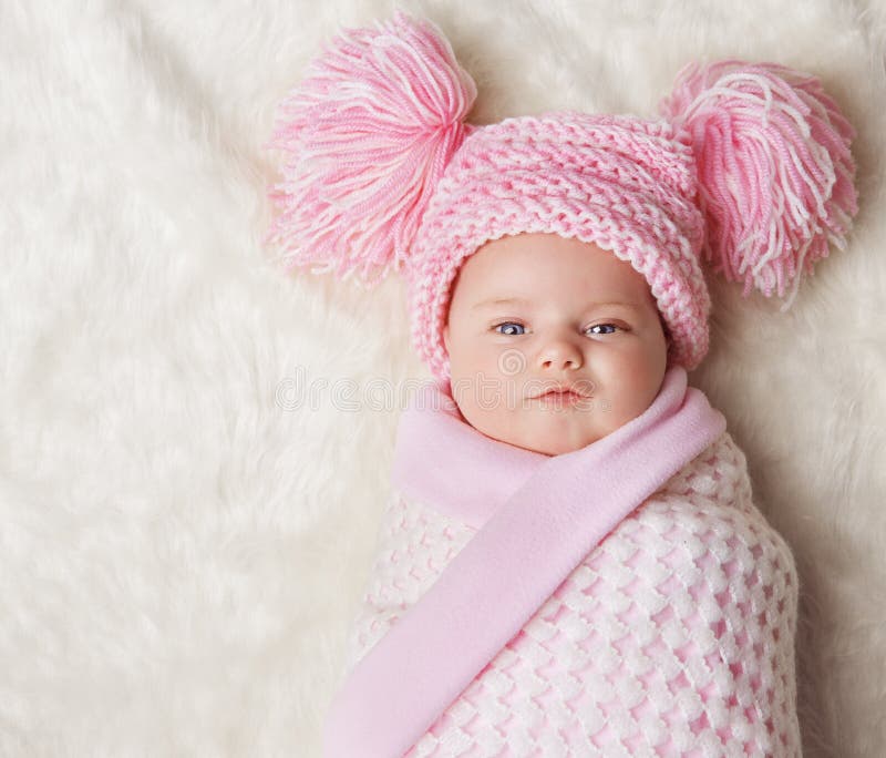 Baby Girl Wrapped Up in Newborn Blanket, New Born Kid Bundled Pink Hat, One Month Child on white Carpet. Baby Girl Wrapped Up in Newborn Blanket, New Born Kid Bundled Pink Hat, One Month Child on white Carpet