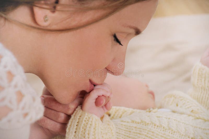 Happy mother kiss hand her newborn baby; sleeping cute baby; maternity concept; soft image of beautiful family. Happy mother kiss hand her newborn baby; sleeping cute baby; maternity concept; soft image of beautiful family