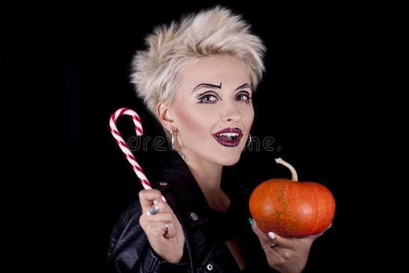 El blonde hermoso con una calabaza y un caramelo en las manos imagenes de archivo El blonde hermoso con una calabaza y un caramelo en las manos imagenes de archivo