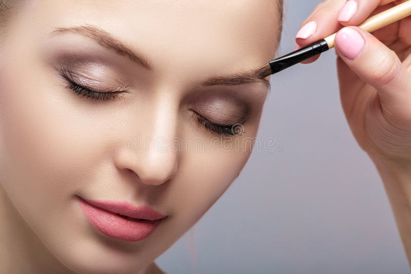 El blonde hermoso de la mujer utiliza el cepillo profesional para el maquillaje de la ceja fotografía de archivo libre de regalías El blonde hermoso de la mujer utiliza el cepillo profesional para el maquillaje de la ceja fotografía de archivo libre de regalías