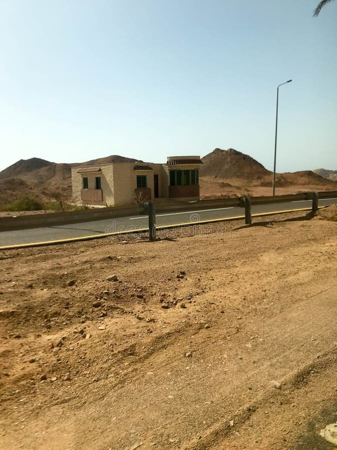 El borde de la carretera, camino con asfalto en el desierto con la arena, topes y faroles, dunas de arena, colinas, montañas y ca imágenes de archivo libres de regalías El borde de la carretera, camino con asfalto en el desierto con la arena, topes y faroles, dunas de arena, colinas, montañas y ca imágenes de archivo libres de regalías