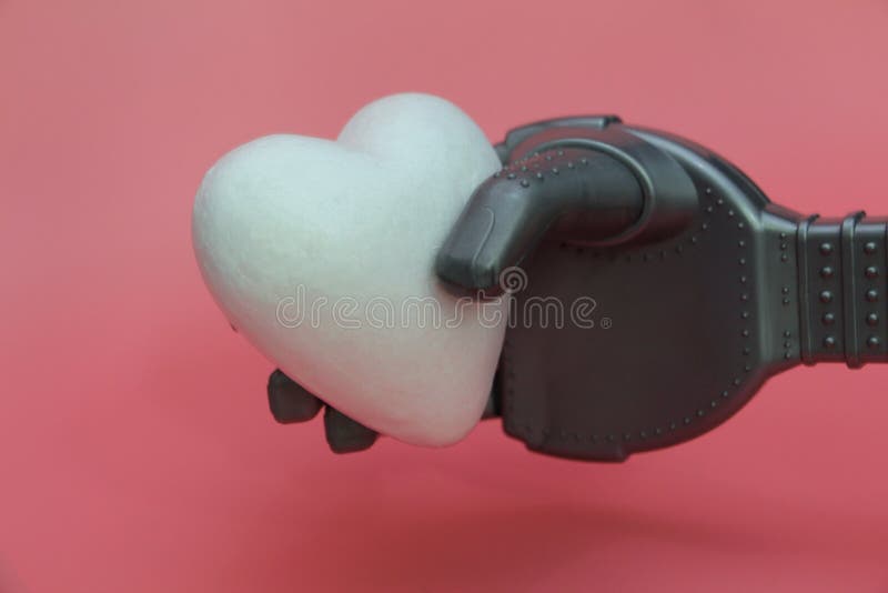 El brazo del hierro de un robot lleva a cabo un corazón blanco Concepto de robots con un corazón fotos de archivo libres de regalías El brazo del hierro de un robot lleva a cabo un corazón blanco Concepto de robots con un corazón fotos de archivo libres de regalías