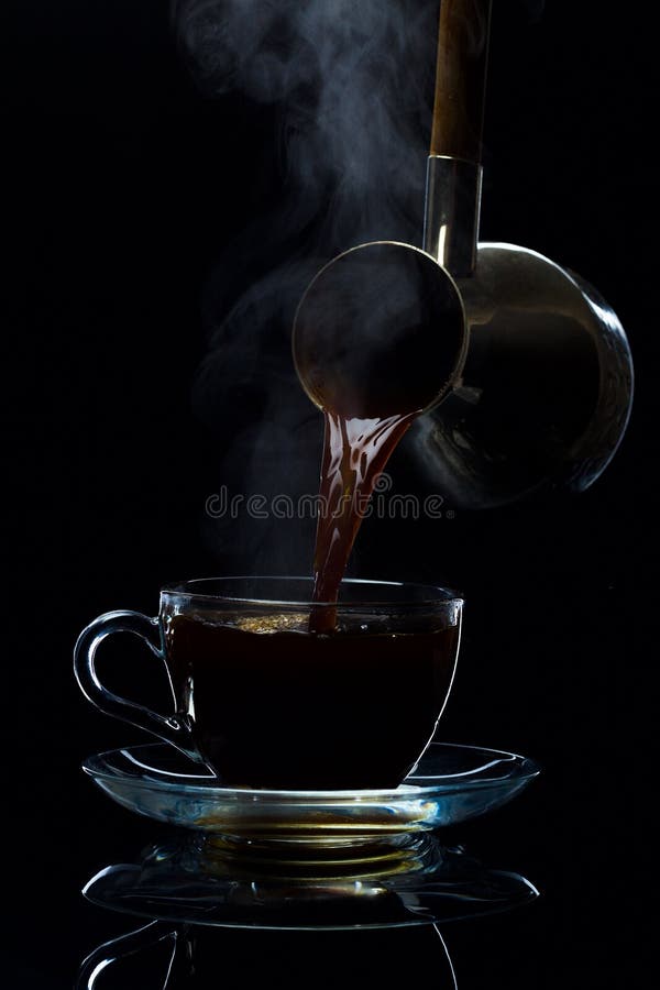 El café se vierte en una taza de cristal de los turcos, un fondo negro imagen de archivo