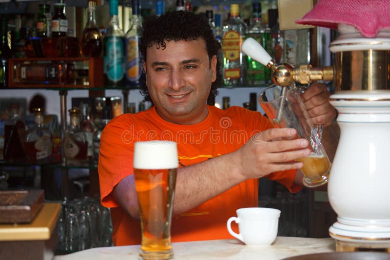 El camarero llena el vidrio de cerveza imagen de archivo libre de regalías El camarero llena el vidrio de cerveza imagen de archivo libre de regalías