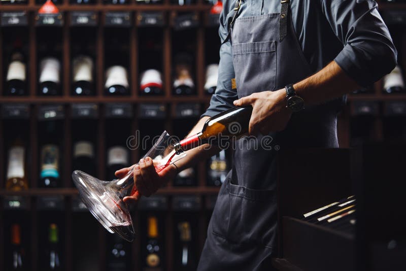 El camarero vierte el vino rojo en buque transparente en sótano fotografía de archivo libre de regalías El camarero vierte el vino rojo en buque transparente en sótano fotografía de archivo libre de regalías
