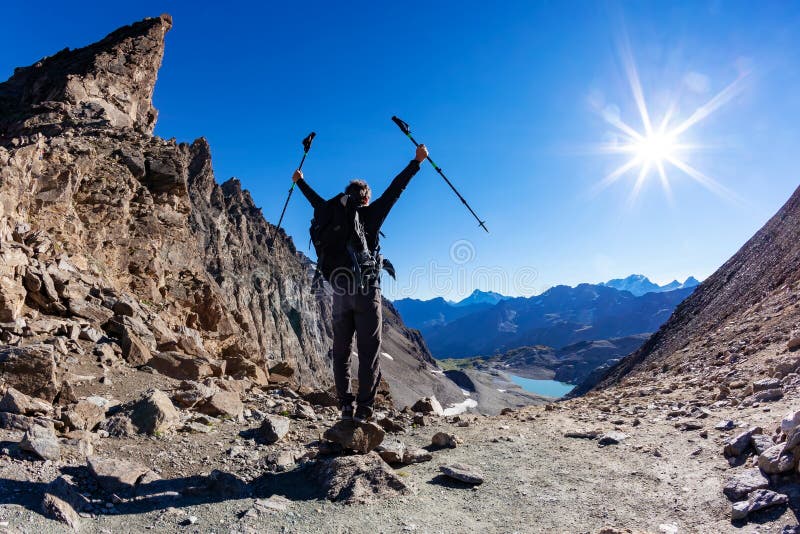 El caminante alcanza un paso de alta montaña; él muestra su alegría en los brazos abiertos imagen de archivo El caminante alcanza un paso de alta montaña; él muestra su alegría en los brazos abiertos imagen de archivo