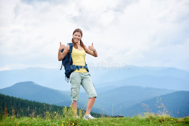 El caminante de la mujer que camina en la colina herbosa, mochila que lleva, usando el senderismo se pega en las monta?as foto de archivo El caminante de la mujer que camina en la colina herbosa, mochila que lleva, usando el senderismo se pega en las monta?as foto de archivo