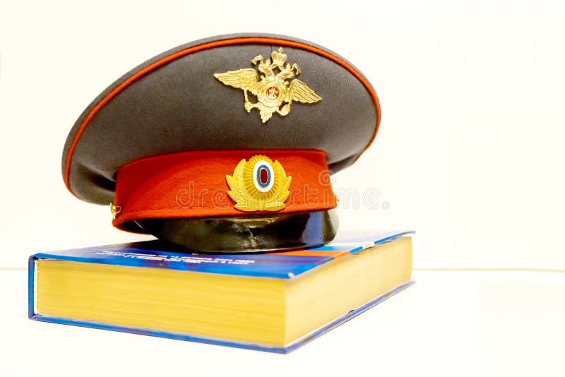 El casquillo de un oficial de policía ruso está en el código de leyes aislante imagen de archivo libre de regalías El casquillo de un oficial de policía ruso está en el código de leyes aislante imagen de archivo libre de regalías