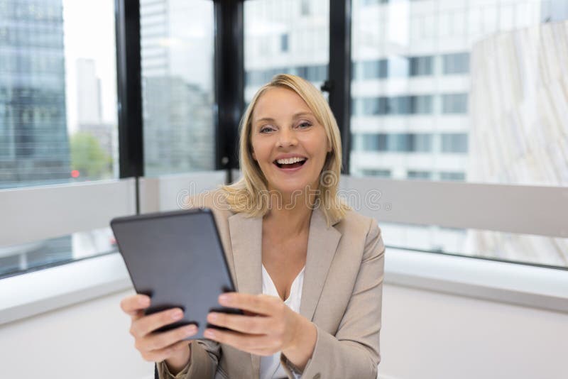 El centro feliz envejeció a la mujer de negocios que usaba la tableta digital Oficina moderna foto de archivo El centro feliz envejeció a la mujer de negocios que usaba la tableta digital Oficina moderna foto de archivo
