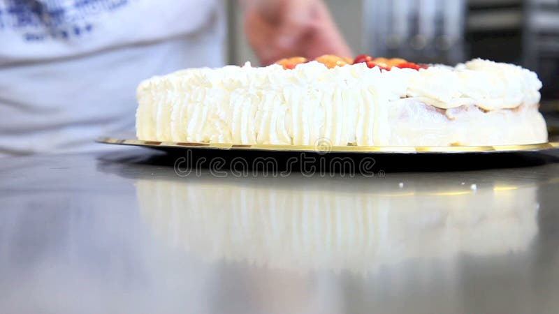 El chef de repostería prepara la torta de la fruta con crema azotada