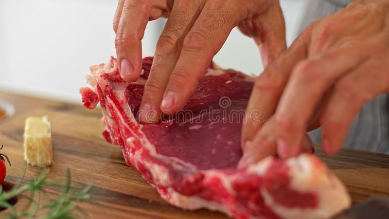 El chef examina la suavidad de la carne en una mesa de cocina de madera almacen de video