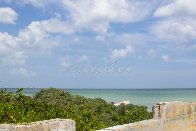 El cielo azul con las nubes en México vio sobre un muro de cemento parcialmente construido con la hierba del mar y pieza de un ba imagen de archivo libre de regalías El cielo azul con las nubes en México vio sobre un muro de cemento parcialmente construido con la hierba del mar y pieza de un ba imagen de archivo libre de regalías