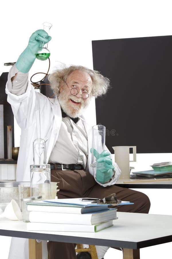 Cheerful mad senior scientist in lab measures green liquid in beaker. Frizzy grey hair, round glasses, lab coat, geek trousers, aqua rubber gloves, blank blackboard, vertical, high key, copy space. Cheerful mad senior scientist in lab measures green liquid in beaker. Frizzy grey hair, round glasses, lab coat, geek trousers, aqua rubber gloves, blank blackboard, vertical, high key, copy space.