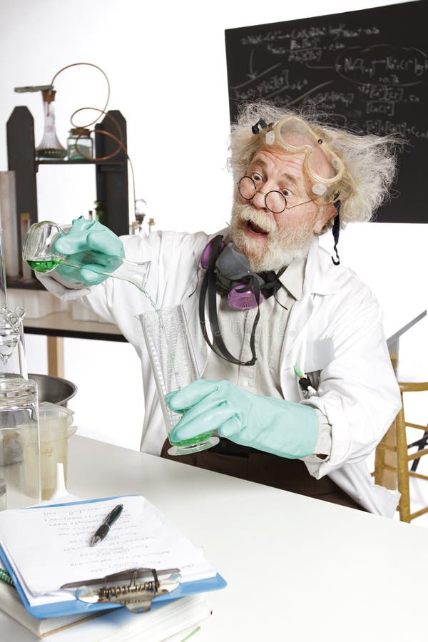 Enthusiastic mad senior scientist in lab measures green liquid in beaker. Frizzy grey hair, round glasses, lab coat, aqua rubber gloves, blackboard, vertical, high key, copy space. Enthusiastic mad senior scientist in lab measures green liquid in beaker. Frizzy grey hair, round glasses, lab coat, aqua rubber gloves, blackboard, vertical, high key, copy space.